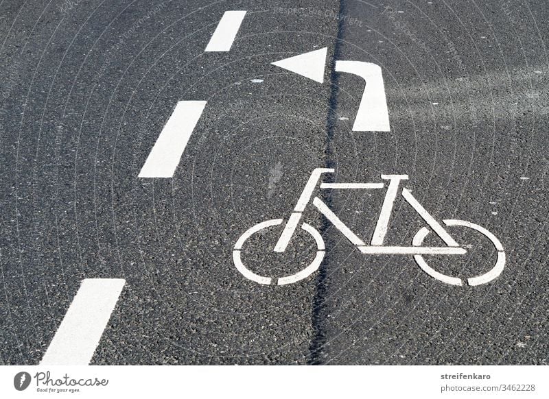 Radfahrer bitte nach links durch die Lücke abbiegen, bedeutete der weiße Pfeil der Fahrbahnmarkierung Straße Straßenmarkierung grau Asphalt Radfahren Radweg