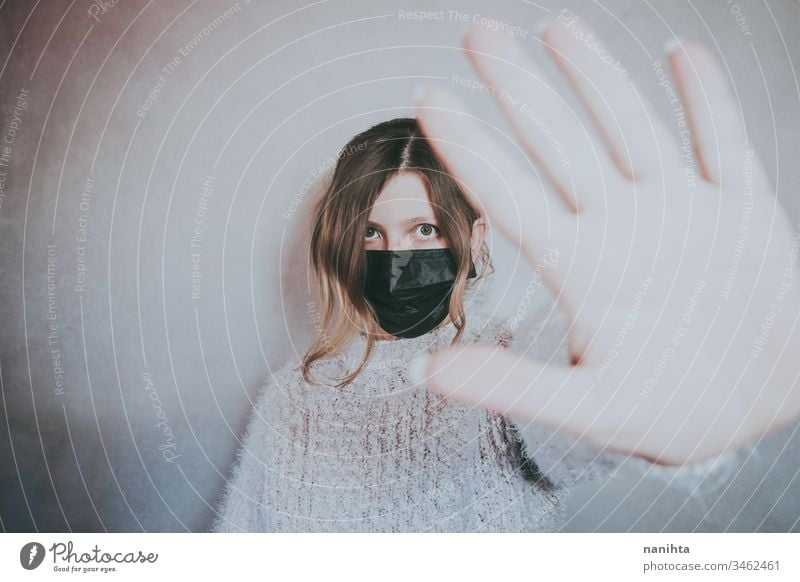Junge Frau, die eine Maske trägt und ihre Hand für soziale Distanz legt Bund 19 COVID Coronavirus Virus Atem Pandemie Mundschutz Krankheit infiziert stoppen