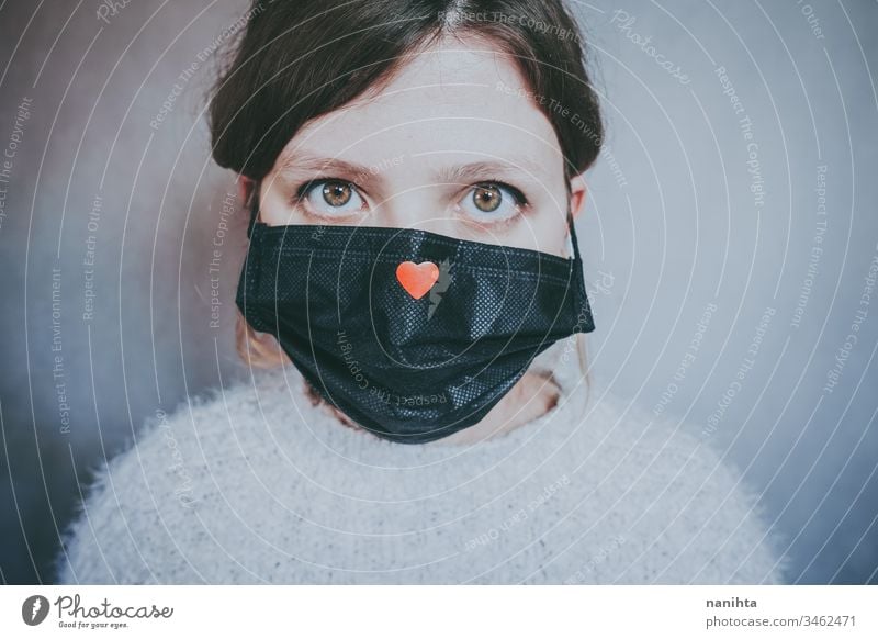 Junge Frau trägt eine Maske mit einem roten Herz Bund 19 COVID Coronavirus Virus Atem Pandemie Mundschutz Krankheit Hoffnung Liebe Hilfsbereitschaft Solidarität