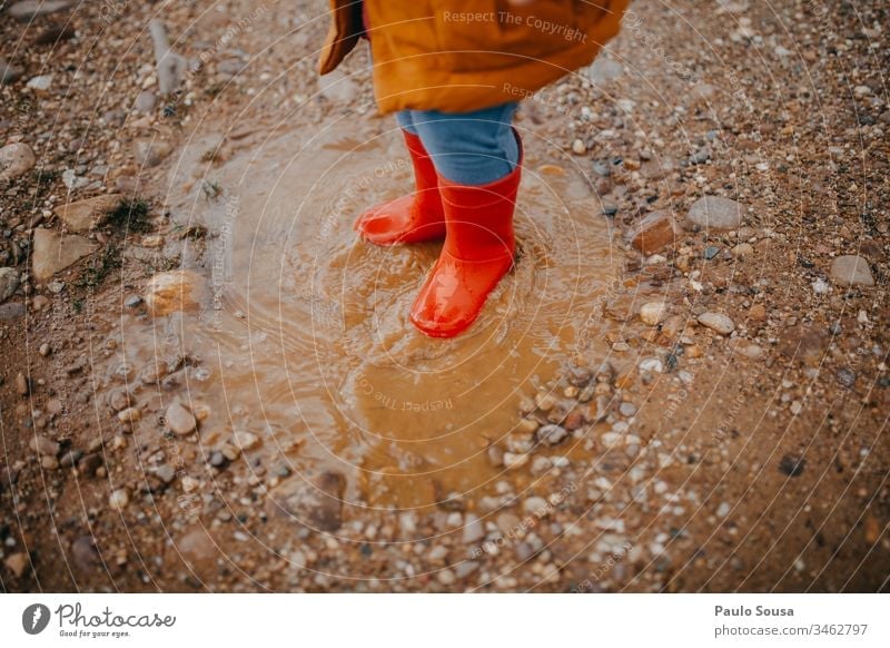 Kinderfüße in roten Gummistiefeln über einer Pfütze Stiefel Regen nass Außenaufnahme Wetter Farbfoto Mensch Freude Wasser dreckig Kindheit schlechtes Wetter