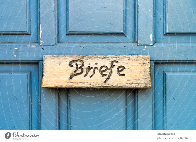 „Schreib mal wieder“ schien die hölzerne Briefkastenklappe in der blauen Tür zu sagen Postkasten Briefe blauer Hintergrund Holz Schreibschrift Haus