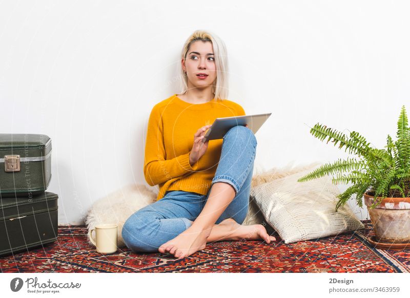 Junge Frau benutzt einen Tablet-Computer, während sie zu Hause auf dem Boden sitzt. Tablette 1 jung heimwärts schön Erwachsener Sitzen Glück