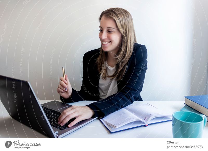 Lächelnde Jungunternehmerin sitzt zu Hause und arbeitet mit ihrem Laptop jung Frau Tisch professionell 1 Geschäftsfrau Sitzen Technik & Technologie Computer
