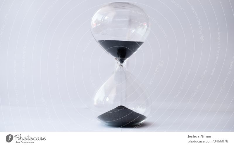 Sanduhr mit auslaufendem schwarzen Sand Hintergrund schwarzer Sand Sanduhr aus schwarzem Sand Uhr Konzept Countdown Frist Eieruhr fließend Zukunft Glas Stunde