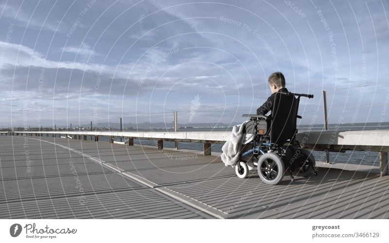 Behindertes Kind ist einsam in dieser großen aktiven Welt. Behinderter Junge im Rollstuhl draußen allein, Aufnahme in Grautönen Handicap deaktiviert Depression
