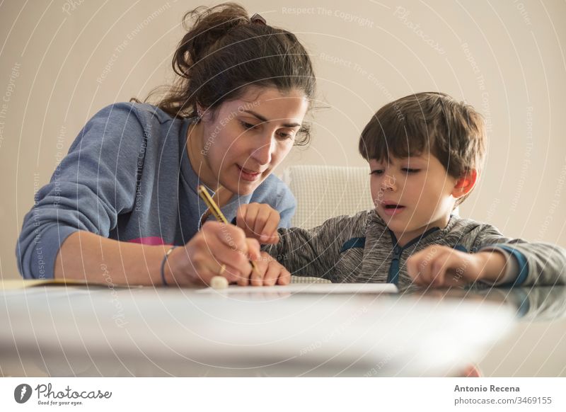 Mutter hilft kleinem Sohn bei den Hausaufgaben zu Hause Kinder Bildung heimwärts Frau Familie Muttertag Liebe schreiben unterrichtete 4s 30s