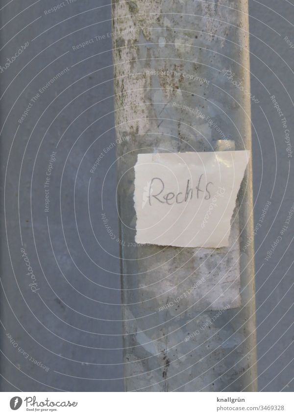 Papierschnipsel mit der Aufschrift „Rechts“ mit zwei Stückchen Klebefilm an einen Laternenpfahl geklebt Zettel Wort Buchstaben abgerissen Schnipsel rechts