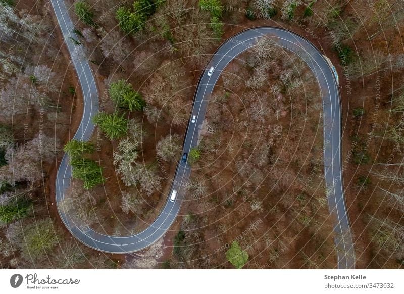 Blick von oben auf eine kurvige Straße von Autos befahren in wäldlicher Landschaft, aufgenommenes Aerial mit einer Drohne Verkehr Kurve wald bäume vegetation
