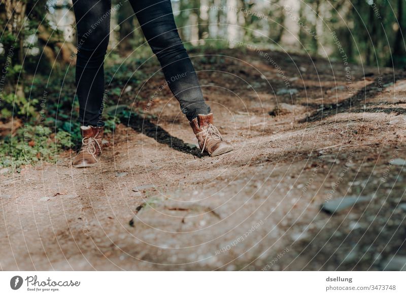 Beine einer jungen Frau mit schwarzer Jeans und braunen Lederstiefeln auf einem Waldweg Wege & Pfade Schuhe Lifestyle wandern Frauenbein