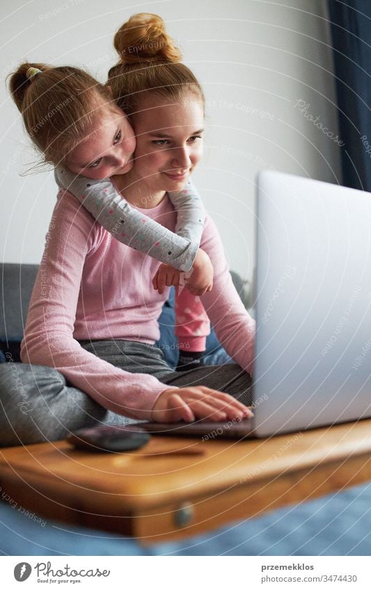 Enkelkinder, Teenagermädchen und ihre jüngere Schwester unterhalten sich während der COVID-19-Quarantäne per Videoanruf mit den Großeltern per Laptop von zu Hause aus. Mädchen sitzen im Bett vor dem Computer