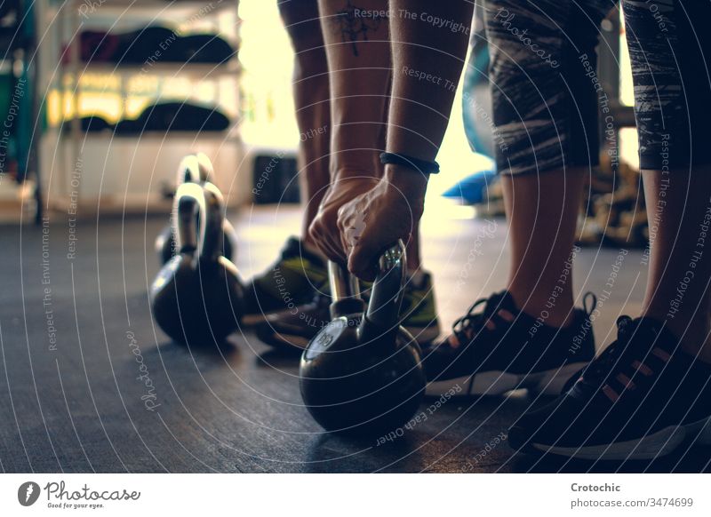 Detail eines Mannes, der eine auf dem Boden einer Turnhalle aufgestellte Kettlebell hält Athlet Fitnessstudio Gewichte Tatkraft trainiert. im Innenbereich