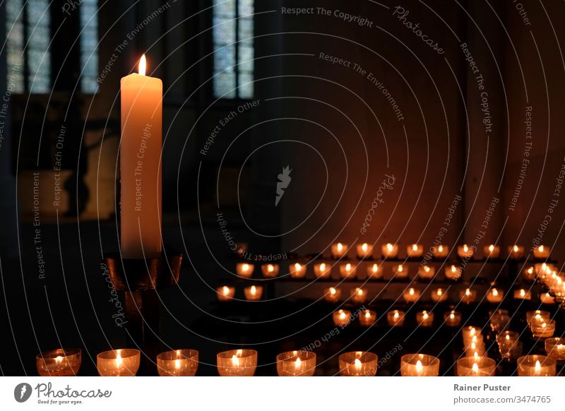 Eine große Kerze und viele kleine Kerzen in einer Kirche Kerzenschein innerhalb einer Kirche Religion Glaube religiös Religion & Glaube Christentum Hoffnung