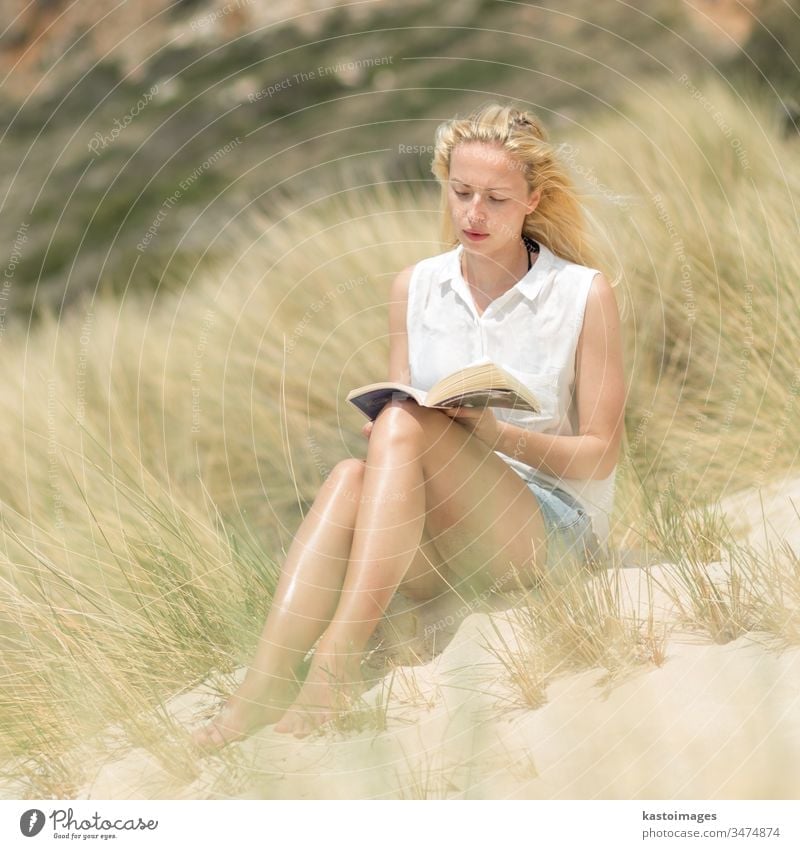 Eine Frau liest ein Buch und genießt die Sonne am Strand. Sommer lesen Natur frei Glück sorgenfrei sich[Akk] entspannen Wind Freude Freiheit Fröhlichkeit