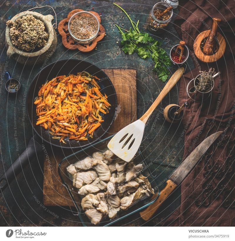 Zubereitung eines Kohlefischgerichts und Gemüsesauce auf dunklem Küchentischhintergrund mit Zutaten, Draufsicht. Konzept für gesunde Hausmannskost. Hausgemachte Küche