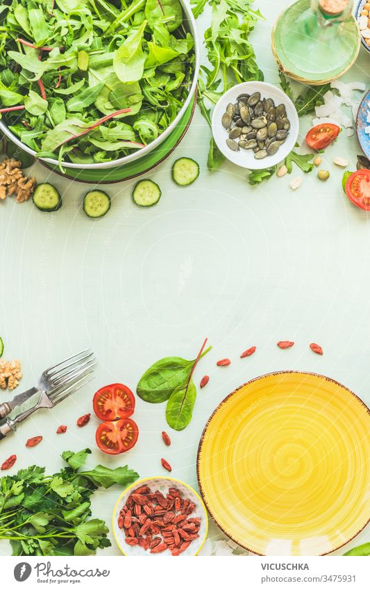 Lebensmittelhintergrund mit Salattellern. Frische grüne Salatzutaten. Salatgarnitur: Samen, Nüsse und Beeren. Gesundes Essen. Hintergrund frisch Salatbeilage