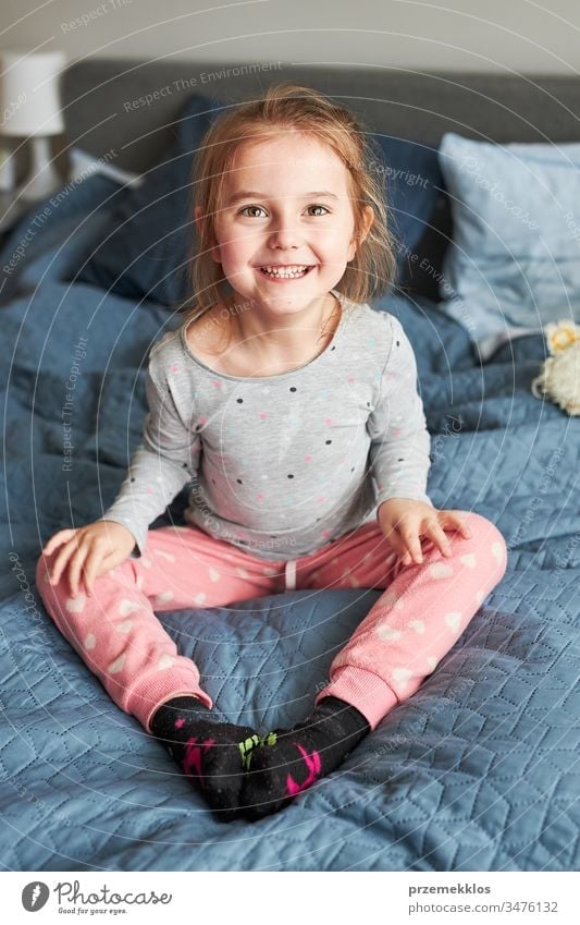 Kleines fröhliches, verspieltes Mädchen, das Spaß daran hat, morgens zu Hause im Schlafzimmer auf das Bett zu springen springend lustig Spielen Herstellung