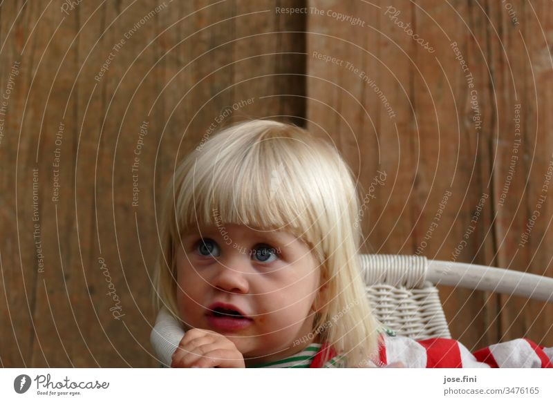 Kleines Mädchen sitzt auf einem Stuhl und blickt mit grossen blauen Augen nach oben Porträt Tag natürlich Liebe blond kleines Mädchen Kind große Augen Gespräch