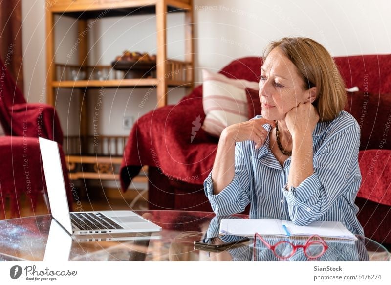 Ältere Frau im mittleren Alter lächelt während sie einen Computer benutzt Laptop reif Menschen Haus Person Lifestyle benutzend Brille Gespräch attraktiv