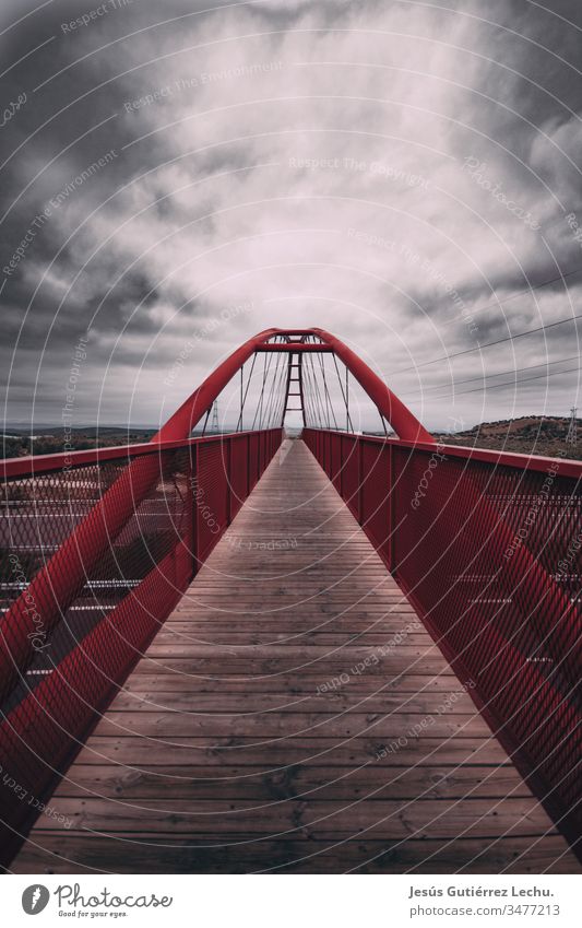 Rote Brücke mit einem langen Holzweg und einem Wolkenhimmel rote Brücke Brückengeländer Brückenkonstruktion Weg könnte Himmel Skyline Straßen Grauwert Spanien