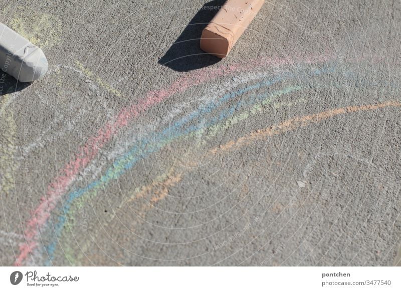 Regenbogen gemalt mit Straßenkreiden und zwei Straßenkreiden regenbogen malen kinderspiel freude kreativität corona symbolik draußen zeitvertreib Kinderspiel