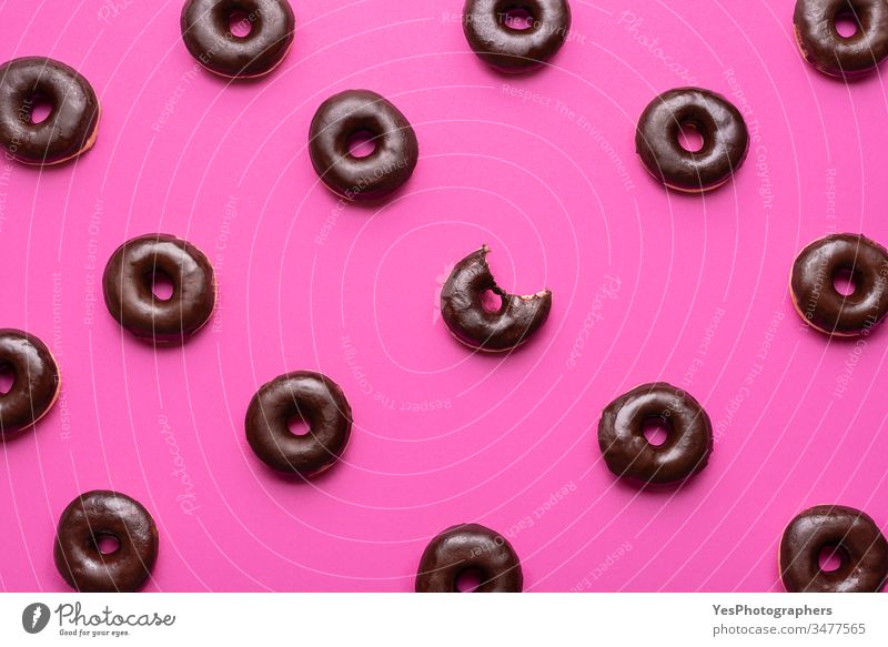 Donuts mit Schokolade glasiert Muster. Ein Doughnut mit fehlendem Biss obere Ansicht verbündet Hintergrund Bagel Bäckerei gebissen Kalorien Kohlenhydrate schoko