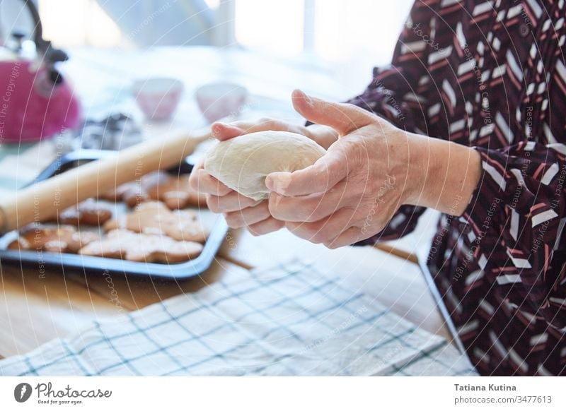 Weibliche Hände einer älteren Frau kneten den Teig. Oma backt Kekse. Heller Hintergrund. Teigwaren Senior Mehl alt Tisch heimwärts Küche Bäcker gealtert