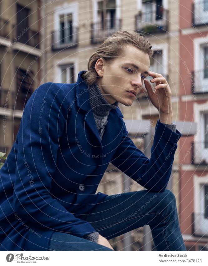 Nachdenklicher Mann in modischer Kleidung sitzt auf der Straße besinnlich nachdenklich Stil trendy ernst Denken urban Großstadt jung männlich elegant modern