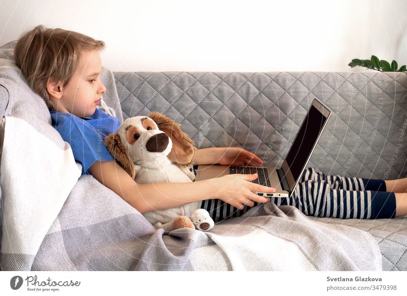 Online-Fernunterricht zu Bildung und Arbeit. Kinder lernen fern von zu Hause auf der Couch. Jungenhände halten Laptop Entfernung online Schule Lernen heimwärts
