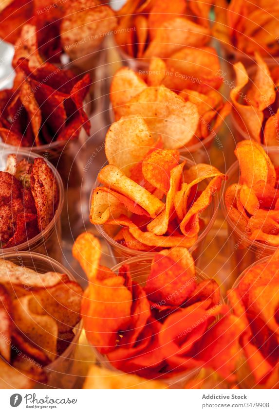 Verschiedene Chips in Plastikbechern zum Verkauf Snack Knusprig Tasse sortiert Lebensmittel Bohnenkraut Würzig Hintergrund orange knirschen lecker geschmackvoll
