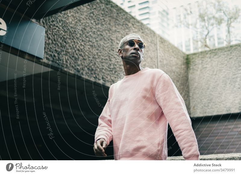 Trendiger afroamerikanischer Mann geht auf der Straße in der Stadt Stil Großstadt modern ethnisch unterirdisch Eingang selbstbewusst urban männlich Outfit