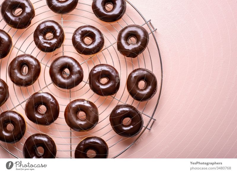 Heiße Donuts mit geschmolzener Schokolade auf einem Kühlgestell. Zubereitung von Schoko-Donuts obere Ansicht ausgerichtet Hintergrund Bäckerei Kohlenhydrate