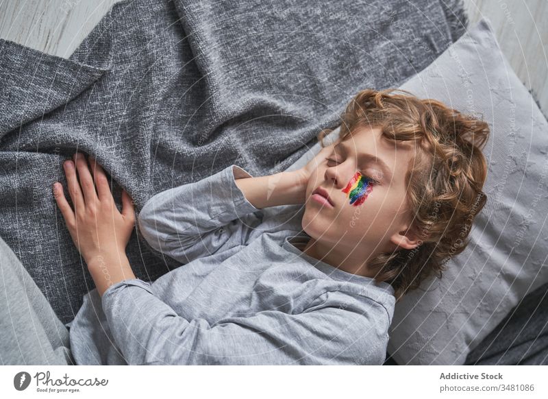 Junge mit Regenbogen im Gesicht schläft auf dem Boden heimwärts Quarantäne schlafen Symbol liegend Stock Kind Decke Kopfkissen Mittagsschlaf Schlummer schlafend
