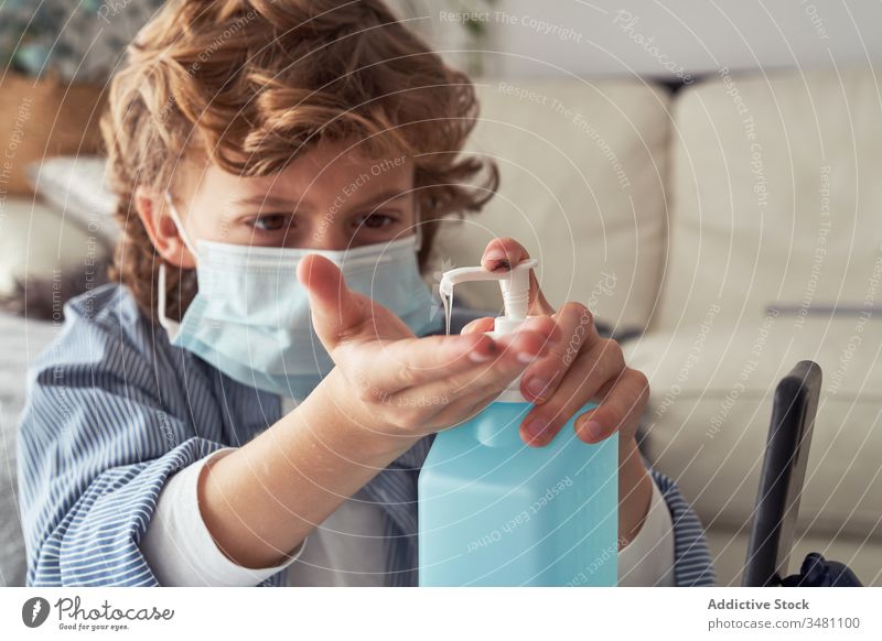 Junge mit medizinischer Maske desinfiziert Hände desinfizieren Hand Quarantäne heimwärts Mundschutz bewerben Flasche Spender Kind Desinfektionsmittel