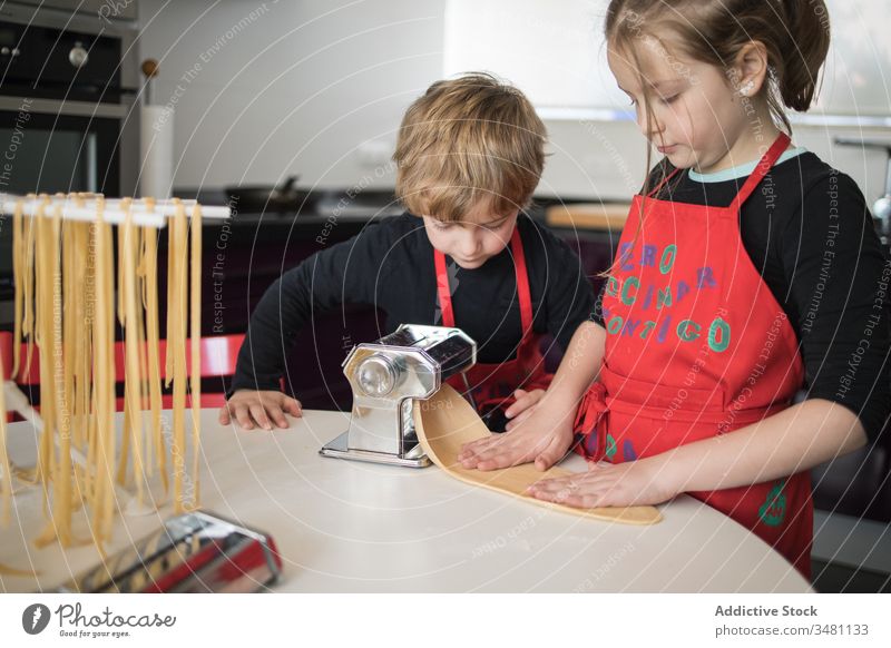 Kinder, die zu Hause Nudeln zubereiten Spätzle machen Maschine Zusammensein Geschwisterkind Küche selbstgemacht vorbereiten geschnitten Schwester Bruder