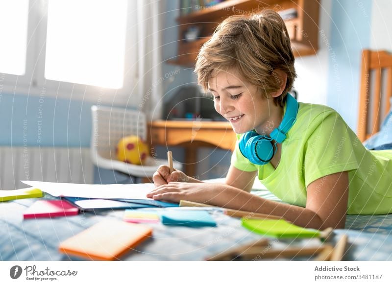 Kleiner Junge malt und hört Musik im Schlafzimmer Kind Kopfhörer zeichnen heiter heimwärts zuhören Kälte Glück farbenfroh Bleistift Drahtlos Lächeln Lifestyle