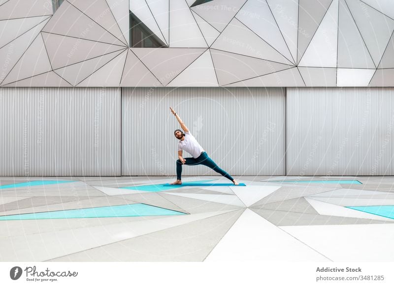 Mann macht Yoga-Übung im geometrischen Raum Training Geometrie Seitenwinkelstellung modern Dehnung Fitness Form männlich Sportbekleidung Architektur Zeitgenosse