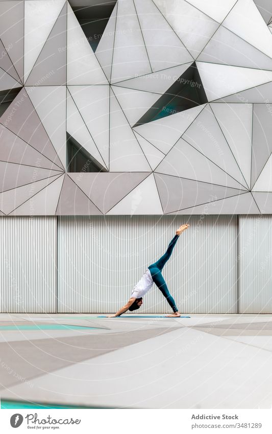 Schlanker Typ führt Yoga-Übung in geometrischem Raum aus Mann Training Geometrie modern Dehnung Fitness Form männlich Sportbekleidung Architektur Zeitgenosse
