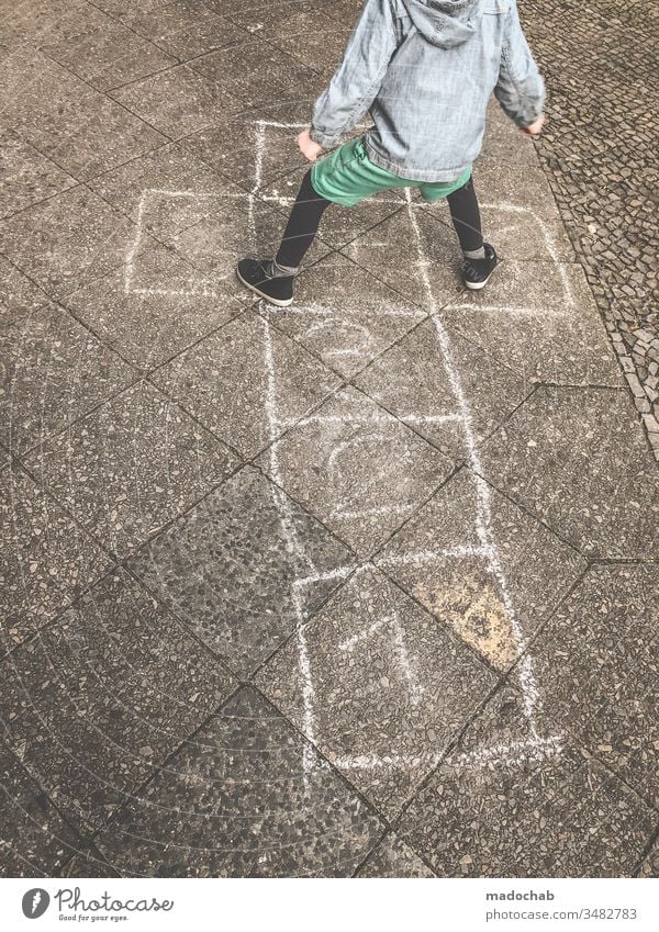 Hickelkasten spielen - Kind springt von Zahl zu Zahl auf mit Kreide gemalten Kästen - altes Kinderspiel Spiel hüpfen springen Spaß Außenaufnahme Spielen