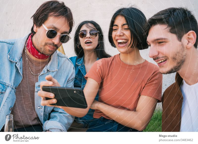 Gruppe von Freunden, die sich etwas auf einem Smartphone ansehen. Mobile Telefon Freundschaft Lifestyle Porträt Beteiligung urban modern Sitzung Freude Genuss