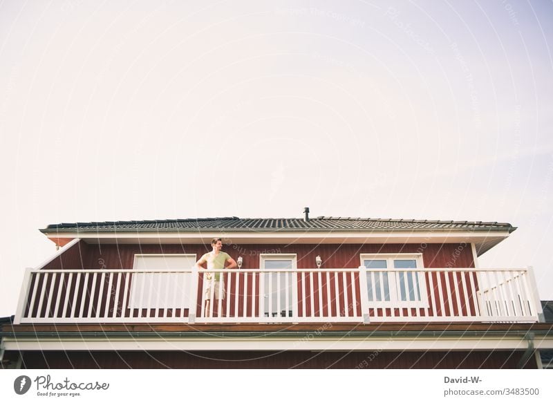 Mann beobachtet vom Balkon aus die Umgebung beobachten gucken Neugier sehen Mensch Blick Erwachsene Farbfoto Außenaufnahme Sommer rot Eigenheim Haus draußen