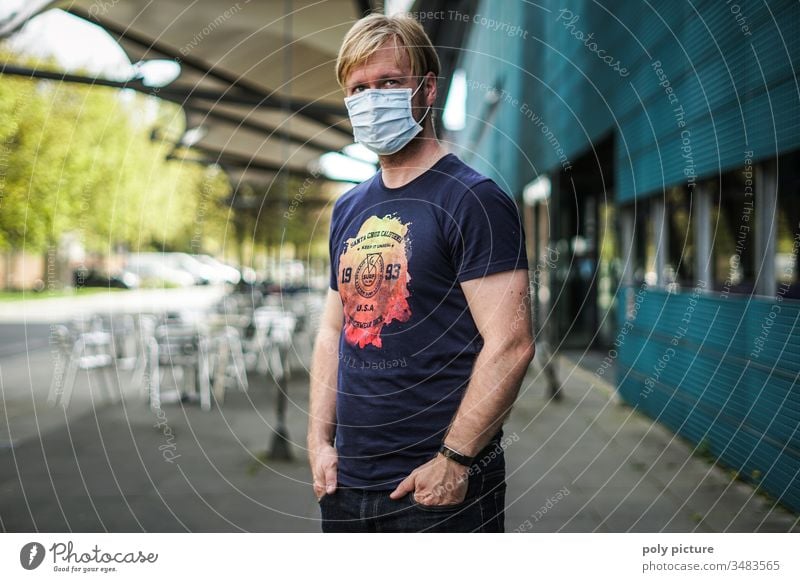 Porträt eines Mannes mit einer Schutzmaske der vor einem Gebäude steht, biologische Gefahr durch Coronavirus: Covid-19-Gefahr Person Epidemie Virus Grippe