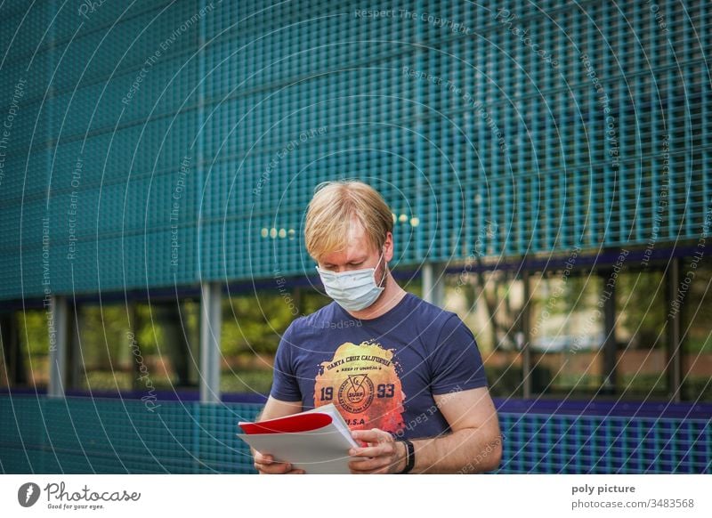 Porträt eines Mannes mit einer Schutzmaske der eine Bericht ließt, biologische Gefahr durch Coronavirus: Covid-19-Gefahr Person Epidemie Virus Grippe