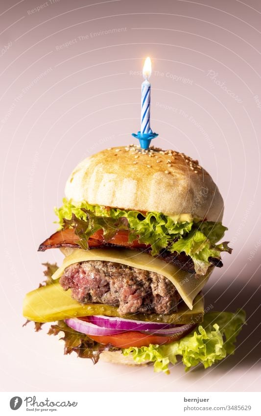 Nahaufnahme eines einzelnen Cheeseburgers Kerze Geburtstag Feier Party Partyfood knusprig fastfood geröstet Bio patty rucola gebacken sesam ketchup Gourmet