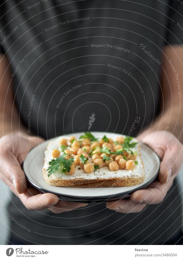 Veganes Sandwich mit Kichererbsen in Männerhänden Belegtes Brot Veganer Hand Zuprosten Teller verzehrfertig Textfreiraum Ideen Gesundheit Frühstück Mittagessen
