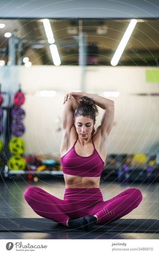 Junge Frau macht Dehnungsübungen auf einer Yogamatte strecken Unterlage Waffen Fitnessstudio Körper passen Bein Mädchen Sitzen Gesundheit Übung Lifestyle