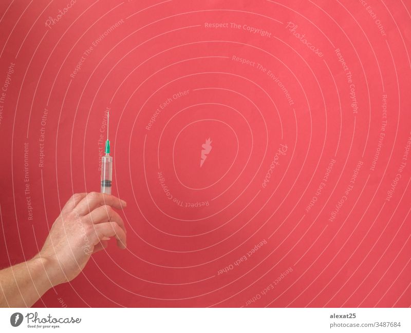 Hand mit Spritze auf rotem Hintergrund mit Kopierfeld Antibiotikum Textfreiraum Coronavirus covid-19 Krankheit Dosis Medikament Seuche Gerät Gesundheit