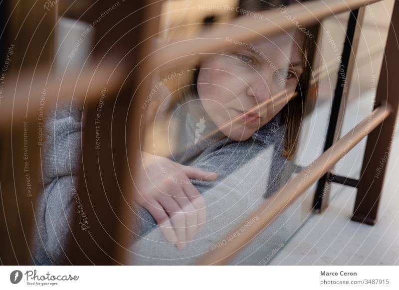 Schöne junge Frau, die melancholisch durch das Glas auf die Straße blickt. Nachdenklich trauriges Mädchen, zu Hause während der Sperre durch Coronavirus isoliert.