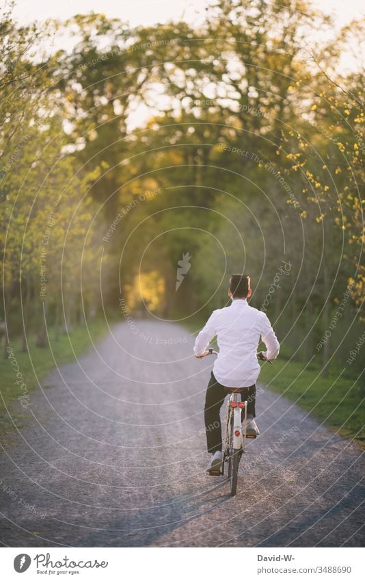 junger Mann fährt mit dem Fahrrad durch die Natur und macht eine Fahrradtour Fahrradfahren Sonnenlicht sommerlich Schönes Wetter spass Freude enstpannung