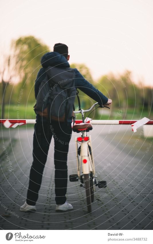 Mann steht mit dem Fahrrad vor einer verschlossenen Schranke. zu abgesperrt stehen warten verbot Absperrung anonym Rückansicht abgeschlossen verboten Sicherheit