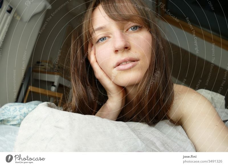 Porträt einer jungen Frau, die morgens im Bett liegt langhaarig Lebensfreude einfach Junge Frau Ponyfrisur Blick in die Kamera hübsch feminin Gesicht schön